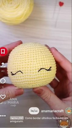 a person holding a yellow ball with eyes drawn on it's face and the words anamaricaraff written in arabic