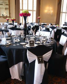 the tables are set with black and white linens, place settings, and centerpieces