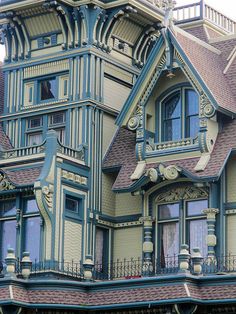 an old victorian style house with blue and white trim on the roof, windows and balconies