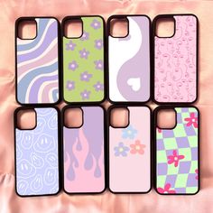 six colorful iphone cases sitting on top of a pink cloth covered tablecloth with flowers and swirls painted on them