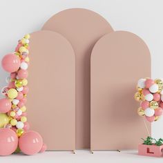 balloon garland and potted plant in front of pink wall with arch shaped archways