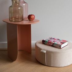 an apple sits on top of a table next to a round stool with a book