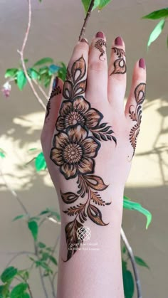 a woman's hand with henna tattoos on it and flowers painted on the palm