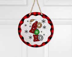 a red and black plaid christmas ornament hanging on a white door with snowflakes