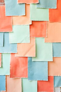 an orange, blue and green wall with some squares on it's side that is made out of colored paper