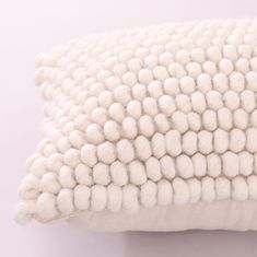 a white pillow with pom - poms on the bottom and back of it