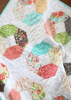 a close up of a quilt on top of a wooden table with a flowered design