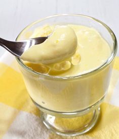 a spoon is in a glass bowl filled with cream and bananas on a checkered tablecloth