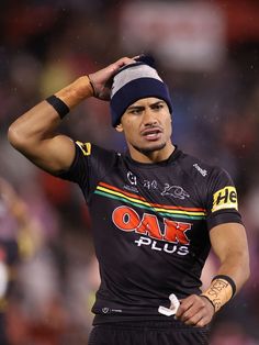 a rugby player is holding his head in one hand and looking at the camera while wearing a beanie