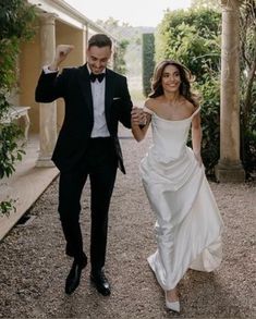 a bride and groom are walking down the path