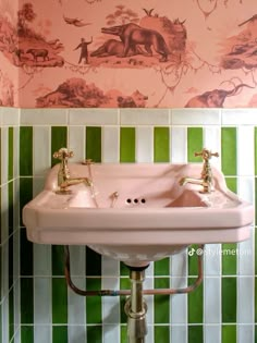 a pink sink in a bathroom with green and white wallpaper on the walls behind it