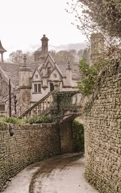 an old cobblestone street with stone walls and houses in the background on a foggy day