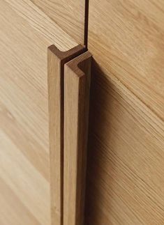 a close up view of a wooden door handle on a cabinet with wood grained finish