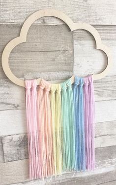 an image of a rainbow cloud with fringes hanging from it's side on a wooden wall