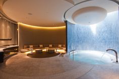 an indoor spa room with a circular jacuzzi tub in the center and seating around it