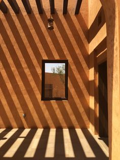 the sun is shining on an orange building with a black door and window in it