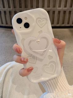 a person holding up a white phone case with hearts on the front and back cover