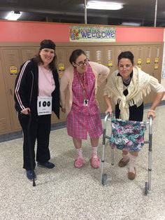 three women standing next to each other with a walker in front of them on the floor