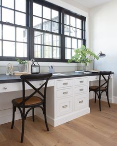 two chairs are sitting at the counter in front of a window with black panes