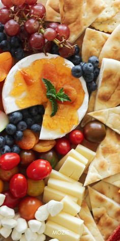 an assortment of cheeses, fruit and crackers arranged on a platter for a party