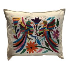 an embroidered pillow with colorful birds and flowers on white linen, the back side is made from