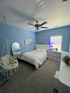 a bedroom with blue walls and grey carpeted flooring, white furniture and a hammock hanging from the ceiling