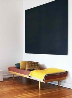 a bed sitting on top of a hard wood floor next to a wall mounted blackboard