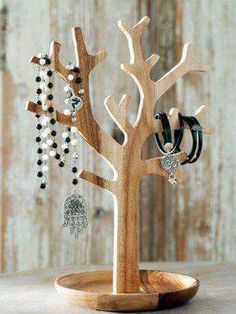 a wooden stand with jewelry hanging from it's sides on top of a table