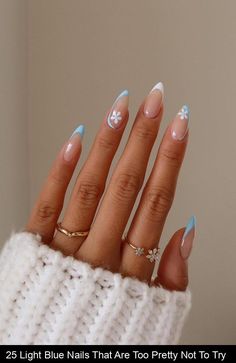 a woman's hand with blue and white nail polish on her nails, wearing a sweater