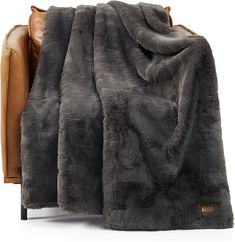 a brown leather chair with a gray blanket on it's back and the seat up