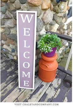 a welcome sign sitting next to a potted plant