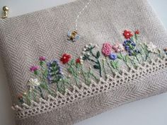 an embroidered purse with flowers and bees on the front is sitting on a white surface