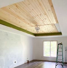 an empty room with hard wood floors and green trim on the ceiling is being painted