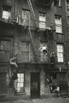 an old black and white photo of people climbing up the side of a building