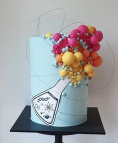 there is a cake decorated with balloons on top of a stand and a bottle in the middle