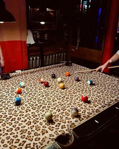 two people are playing pool on an animal print table