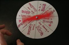 a hand is pointing at a wheel that has words on it with red markers