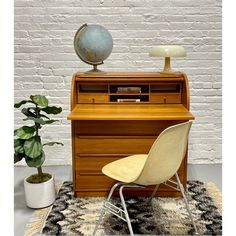 a desk with a chair and a globe on top of it next to a potted plant