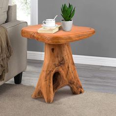 a small wooden table with a potted plant on it next to a couch in a living room