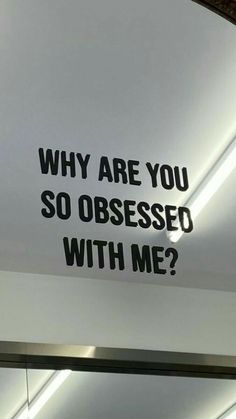 a sign that says, why are you so obsesed with me? on the wall