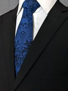 a man in a suit with a skull on it's lapel and a blue tie