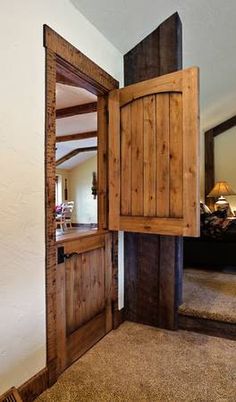 an open wooden door in the corner of a room with carpeted floor and walls