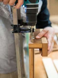 a person using a drill to attach a piece of wood with a machine on it