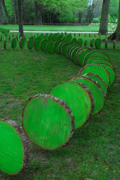 a row of green logs sitting on top of a grass covered field next to trees