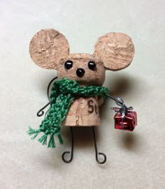 a wooden mouse with a green scarf around it's neck holding a red present