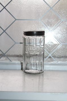 a glass jar sitting on top of a counter next to a tile backsplash