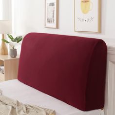 a bed with a red pillow on top of it next to a white wall and pictures