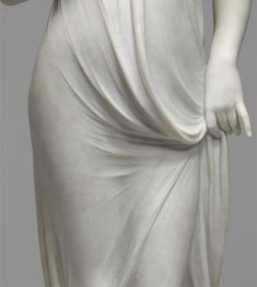 a white statue wearing a dress and holding a cell phone