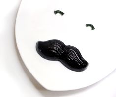 a white plate topped with a black moustache on top of it's side