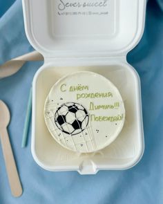 a cake with a soccer ball on it in a box next to utensils